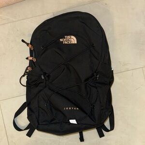 Black North Face backpack featuring a baby pink logo. In great condition.